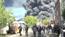 Local officials are pictured in Tuapse, a Black Sea port in southwestern Russia, on April 28 as smoke from a massive blaze rises in the background. Ukraine launched drone strikes on the oil refinery for the third time in two weeks.<br>