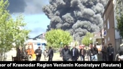 Local officials are pictured in Tuapse, a Black Sea port in southwestern Russia, on April 28 as smoke from a massive blaze rises in the background. Ukraine launched drone strikes on the oil refinery for the third time in two weeks.<br>