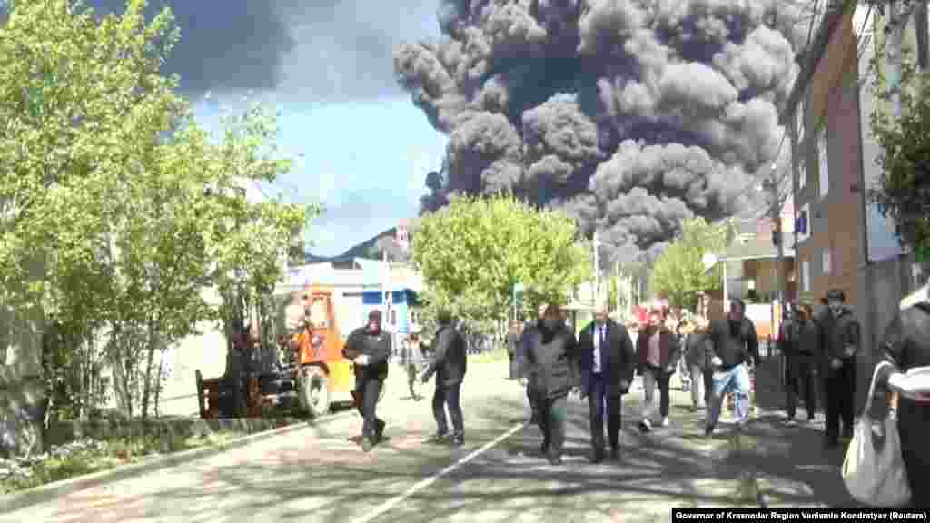 Local officials are pictured in Tuapse, a Black Sea port in southwestern Russia, on April 28 as smoke from a massive blaze rises in the background. Ukraine launched drone strikes on the oil refinery for the third time in two weeks.