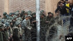 Egyptian soldiers prevent demonstrators from crossing over a barbed-wire fence as thousands gather near the presidential palace in Cairo to protest against a draft constitution and President Muhammad Morsi's sweeping decree.