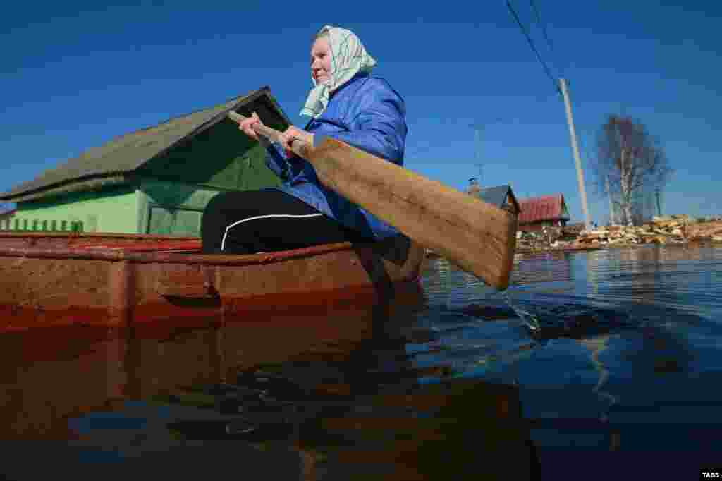 An elderly woman paddles a small boat on a flooded street in the Russian village of Kholui in the Ivanovo region. (TASS)