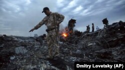 People walk among the debris at the MH17 crash site near the village of Hrabove in the Donetsk region on July 17, 2014.