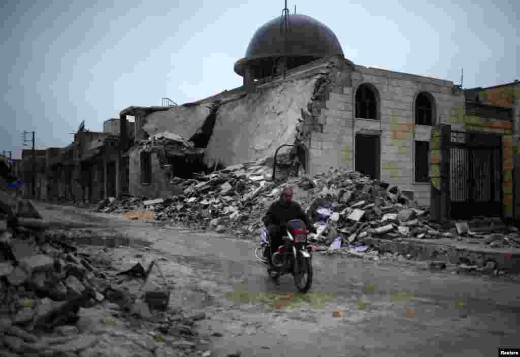 A man rides a motorcycle past a mosque destroyed by a government air strike in Syria's Azaz city. (Reuters/Ahmed Jadallah)