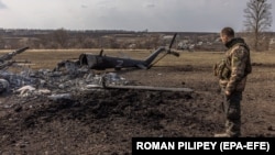 Український військовий біля знищеного російського гелікоптера у відбитому українською армією селі Мала Рогань поблизу Харкова, 31 березня 2022 року