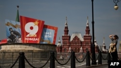 Žena stoji na ulici ukrašenoj plakatima povodom Dana pobjede u centru Moskve, 6. maja 2026.