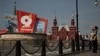 A woman stands in a street with Victory Day decorations and Red Square in the background, in central Moscow on May 6, 2026.