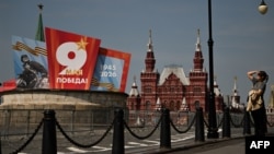A woman stands in a street with Victory Day decorations and Red Square in the background, in central Moscow on May 6, 2026.