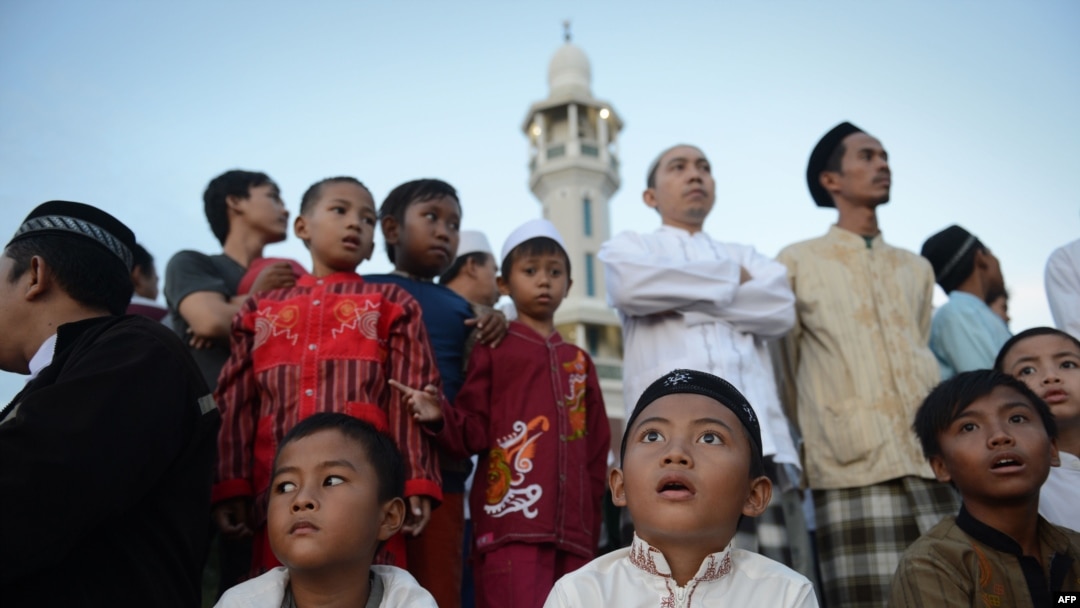 Indonesian children and elder Muslim men prepare to sight the new moon from the rooftop of the Al-Hidayah Basmol Mosque in Jakarta on July 8.