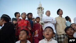 Indonesian children and elder Muslim men prepare to sight the new moon from the rooftop of the Al-Hidayah Basmol Mosque in Jakarta on July 8.