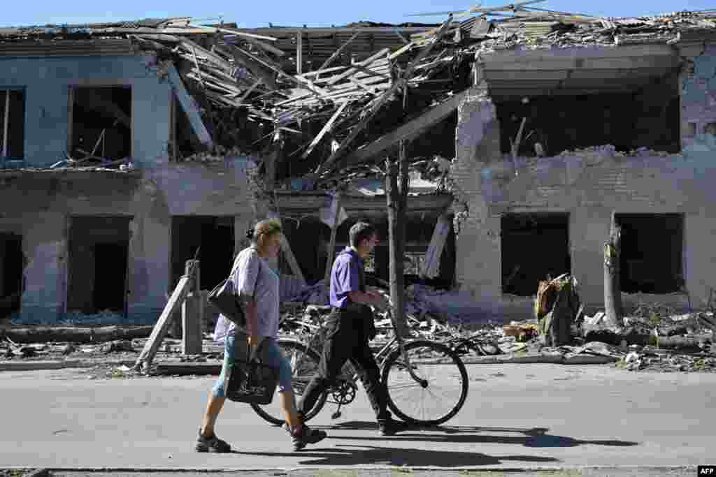 Local residents walk past a heavily damaged building following a Russian strike in the city of Pokrovsk in Ukraine&#39;s Donetsk region.&nbsp;