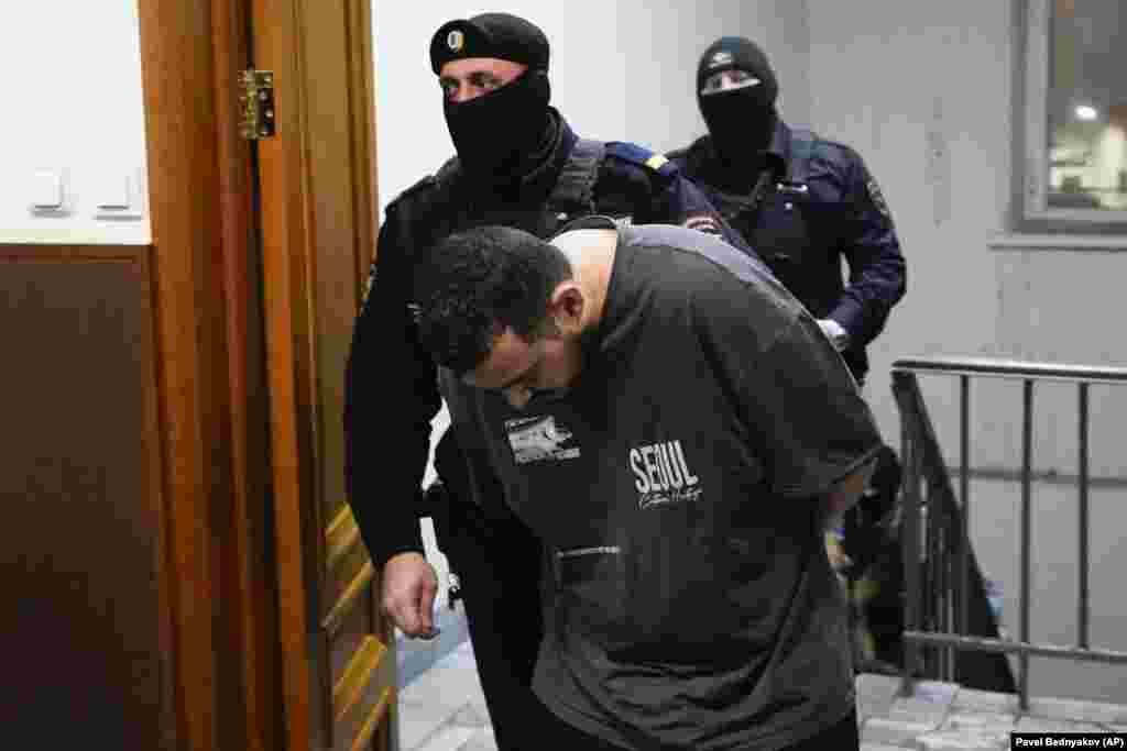 Akhmadzhon Kurbonov, an Uzbek citizen suspected of involvement in the killing of General Igor Kirillov in Moscow, is escorted to a courtroom at the Basmanny District Court on December 19.