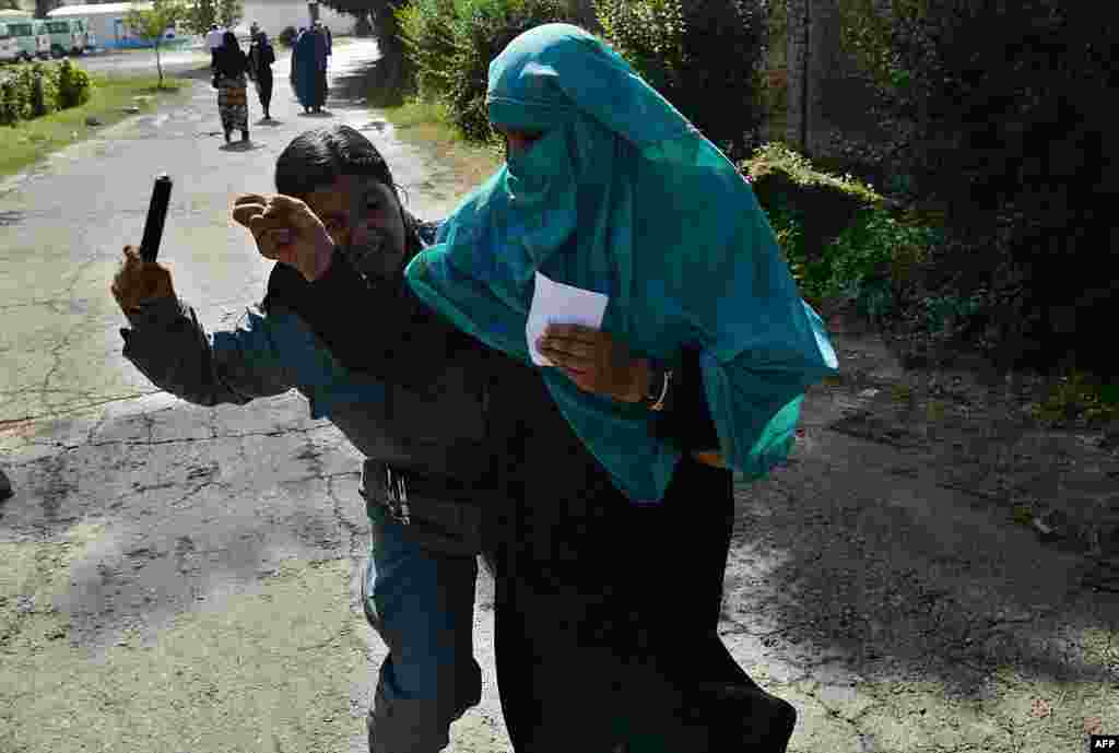 An Afghan police officer beats a woman as she waits for a food donation during the month of Ramadan in Kabul on August 1. (AFP/Shah Marai)