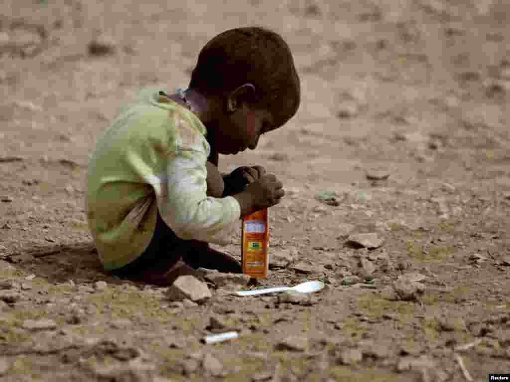 A child, displaced for a year by Pakistan's deadly flooding, plays with an empty juice box outside his family tent while taking refuge along a road in Jamshoro, north of Karachi, on July 25. Photo by Akhtar Soomro for Reuters