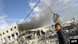 A Palestinian boy stands in front of a destroyed building in Gaza City on December 27 