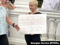 აქციის მონაწილე საპროტესტო პლაკატით