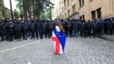 A demonstrator draped in the Georgian national and EU flags stands in front of a police cordon during an opposition protest in Tbilisi. (file photo)