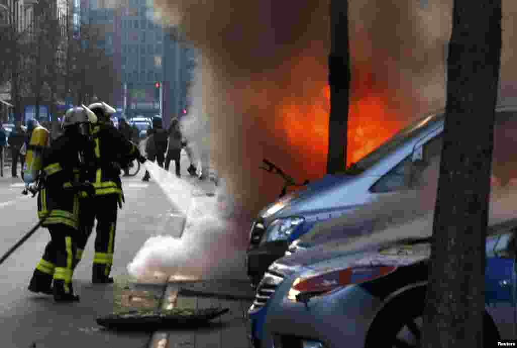 Пожарные тушат один из полицейских автомобилей, подожженных прямо у нового здания Европейского центробанка