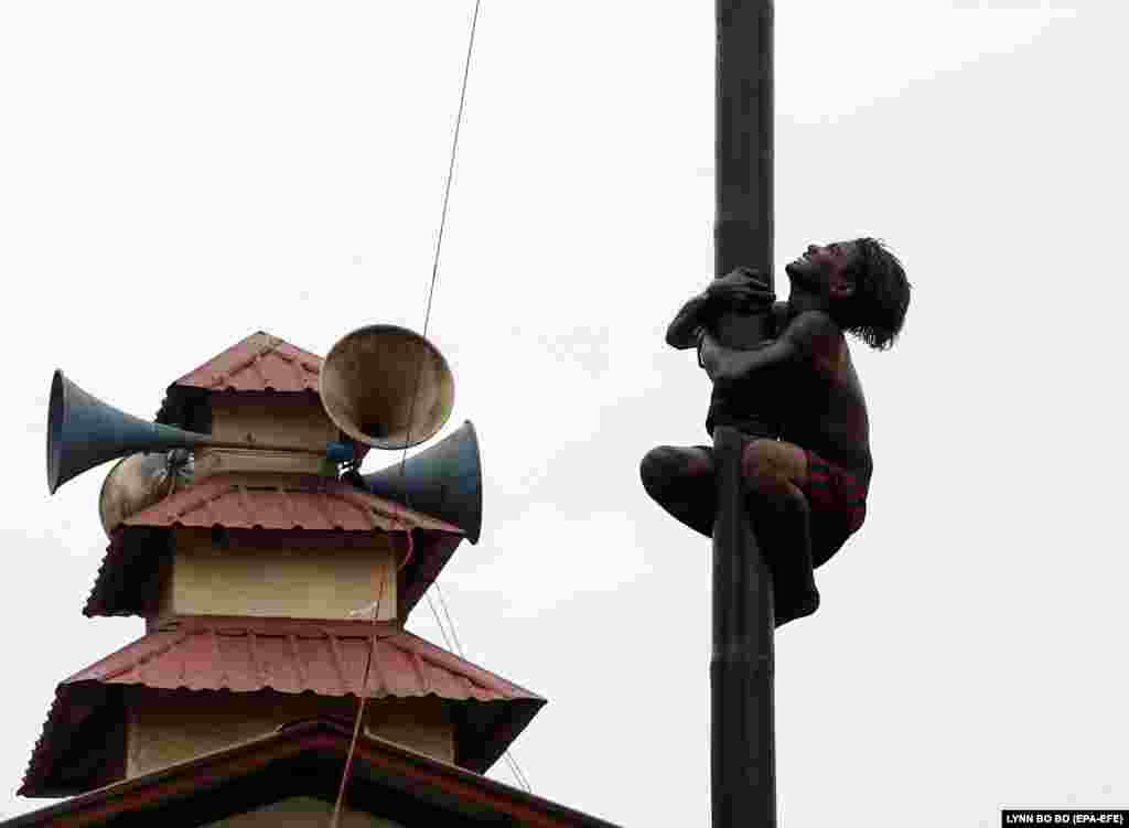 A Burma man tries to climb to the top of slippery bamboo pole, covered with lubricating oil, as he participates in a competition on the occasion of the 70th anniversary of Burma's Independence Day in Yangon. (epa-EFE/Lynn Bo Bo)