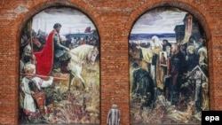Женщина перед стеной Коломенского кремля с картиной, на которой изображен Дмитрий Донской