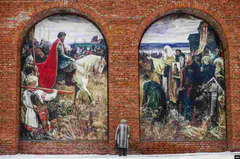 A Russian woman stands in front of the wall of the Kolomna Kremlin with huge painting of Dmitry Donskoy Assembles An Army Against The Tatars, in Kolomna, Russia. (epa/Sergei Ilnitsky)