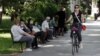A women rides a bicycle past people waiting for a bus in Podgorica on May 25. 