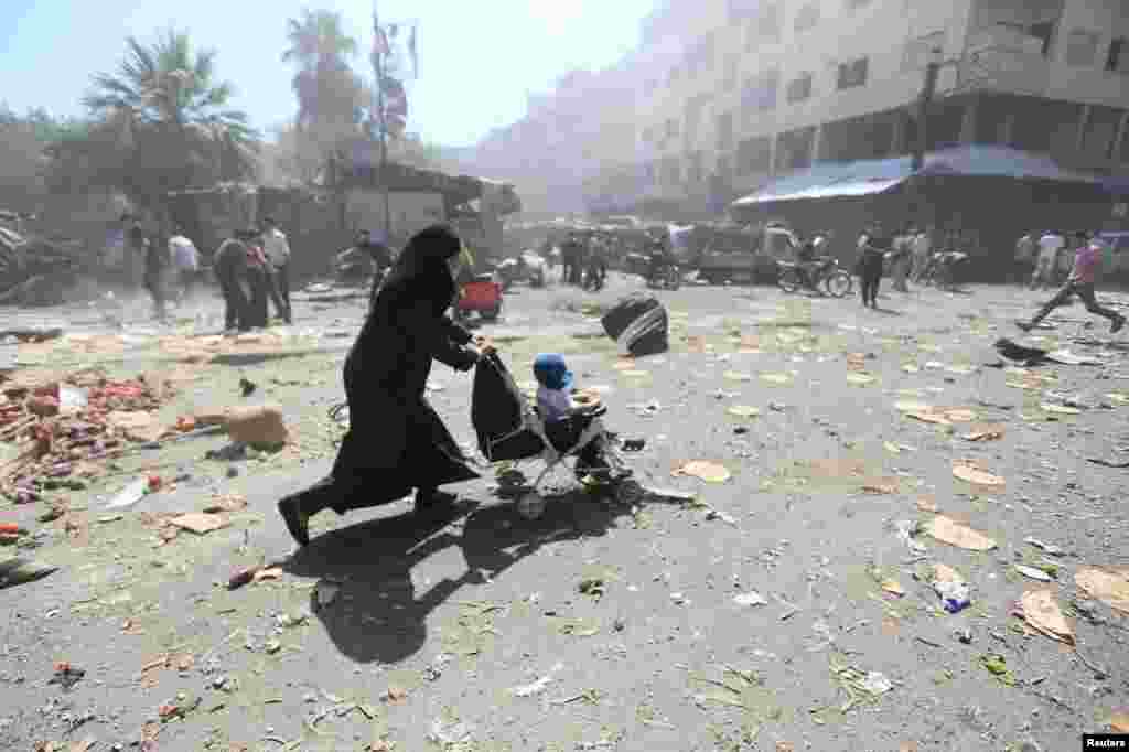 A woman pushes a baby stroller in the aftermath of what activists said were air strikes by forces loyal to Syrian President Bashar al-Assad in Damascus, Syria.&nbsp;(Reuters/Bassam Khabieh)
