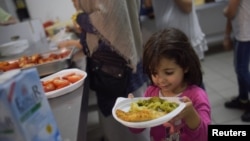 Девочка с едой в лагере для беженцев в Берлине. 9 июня 2016 года.