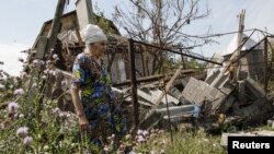 Жінка біля свого зруйнованого будинку в Донецькій області