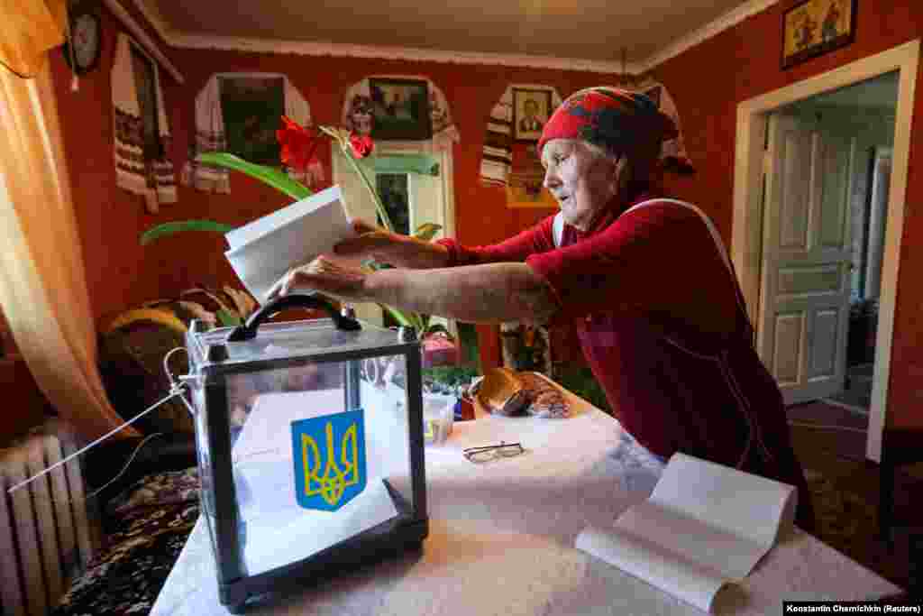 A local resident casts her vote into a mobile ballot box in a house in the village of Velyka Buhayivka in the Kyiv region. (Reuters/Konstantin Chernichkin)