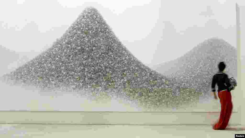 A visitor walks past "Ash Colour Mountains," an acrylic on canvas by Japanese artist Makoto Aida. 