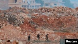 Fighters from the Syrian Islamist rebel group Jabhat Fateh al-Sham, the former Al-Qaeda-affiliated Al-Nusra Front, patrol amid the rubble in southwestern Aleppo, Syria, on August 5.
