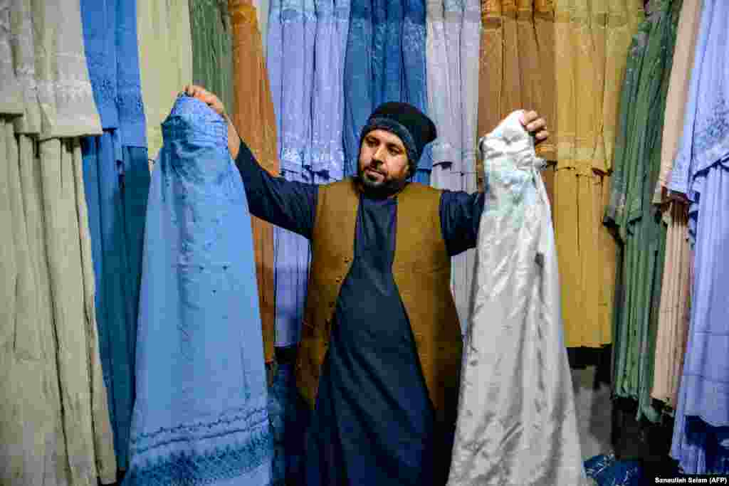 After: An Afghan shopkeeper shows burqas of different colors to a customer in the southern city of Kandahar in February 2025.