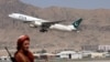 Боевик «Талибана» стоит в аэропорту Кабула на фоне взлетающего самолета «Пакистанских авиалиний», который совершил первый коммерческий международный рейс после прихода к власти талибов в прошлом месяце. 13 сентября 2021 года