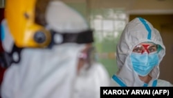 Védőeszközöket viselő egészségügyi személyzet tagja 2020. április 30-án felkészül egy koronavírusos beteg kezelésére a kistarcsai kórházban