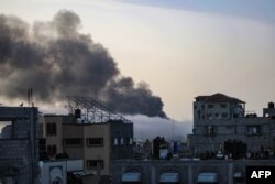 Fumul se ridică deasupra unei clădiri la răsăritul soarelui, în urma unui bombardament israelian la Rafah, în sudul Fâșiei Gaza, la 10 mai 2024, în contextul conflictului actual dintre Israel și mișcarea palestiniană Hamas.