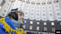 A woman with a national flag around her shoulders attends an opposition rally in front of the Cabinet of Ministers building in downtown Kyiv on November 27.