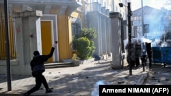Një protestues hedh gurë drejt policisë pranë Ministrisë së Arsimit në Tiranë më 24 tetor. 