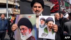 A Shi'a Muslim cleric poses with pictures of Iran's new supreme leader, Ayatollah Mojtaba Khamenei (right), and his late father, Ali Khamenei, during a pro-government rally in central Tehran on March 9. 