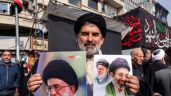 Шиитски муслимански свештеник држи слики од новиот врховен водач на Иран, ајатолахот Моџтаба Хамнеи (десно), и неговиот покоен татко, Али Хамнеи, за време на провладин митинг во центарот на Техеран на 9 март 2026 година