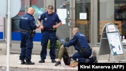 Police officers stand next to a person lying on the sidewalk in the Finnish city of Turku on August 18.