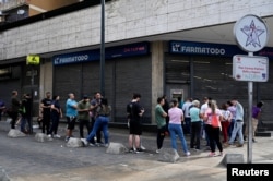 Людзі стаяць у чарзе ў аптэку ў Каракасе