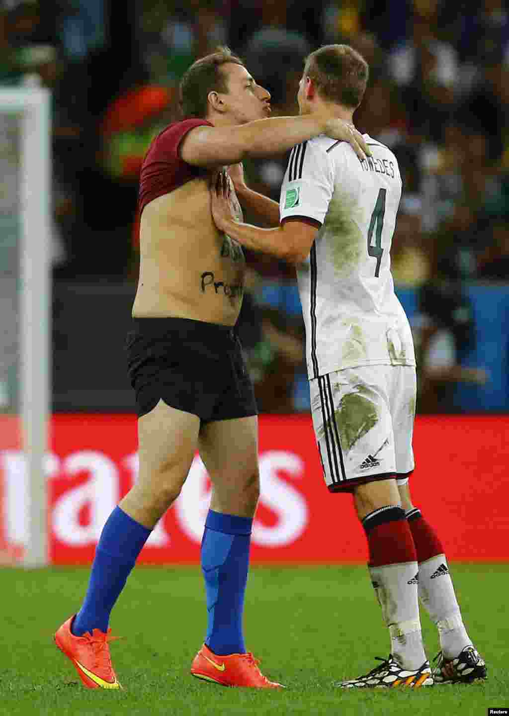 Germany's Benedikt Hoewedes (R) pushes away a fan who invaded the pitch during the team's 2014 World Cup final against Argentina at the Maracana stadium in Rio de Janeiro July 13, 2014. 