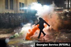 Maskirani policajac šuta dimnu bombu 29. novembra tokom druge noći protesta nakon što je gruzijska vlada objavila da će obustaviti pregovore o pristupanju EU.