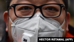 Një persona me maskë, teksa tenton të mbrohet nga virusi i ri në Kinë.