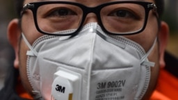 شهروند چینی در شهر شانگهای چین در حالی که بر صورت ماسک زده در ۲۲ ژانویه؛ پژوهشگران و دانشمندان در تلاش هستند تا به رد پای ویروس در مراحل اولیه شیوع آن دست پیدا کنند.