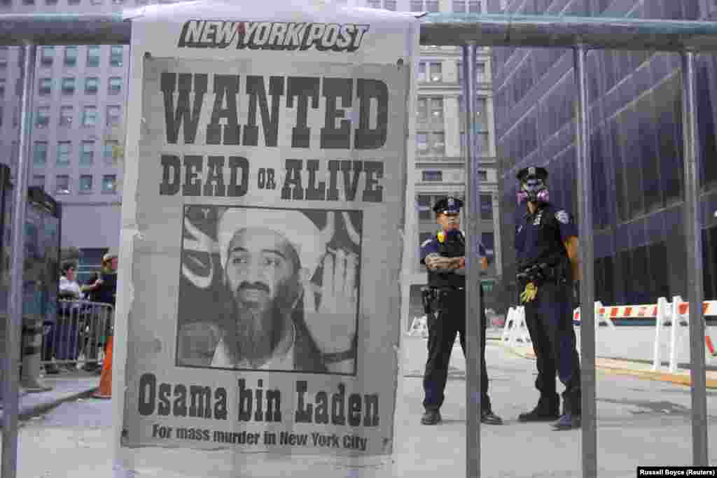 Polițiști din New York și prima pagină a ziarului New York Post din 18 septembrie 2001 - ziarul îl prezintă pe Osama bin Laden, liderul Al-Qaeda și creierul atentatelor din 11 septembrie 2001. Președintele George W. Bush l-a identificat pe bin Laden drept principalul suspect în atacurile de la New York și Washington.