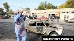 AZERBAIJAN -- An investigator walks near a burnt car after shells hit a street in the town of Barda, October 28, 2020.