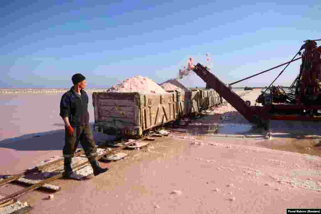 A worker walks past a wagon as it is loaded with pink sea salt&nbsp;at Lake Sasyk-Sivash, near the city of Yevpatoria, Crimea.