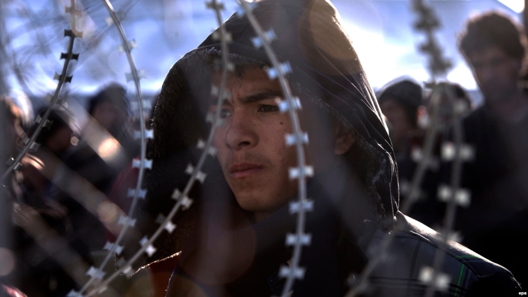 Afghan migrants who have no permission to cross the border between Greece and Macedonia stand behind a fence near Gevgelija.