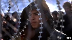 Afghan migrants who have no permission to cross the border between Greece and Macedonia, stay behind a fence, near Gevgelija in February.